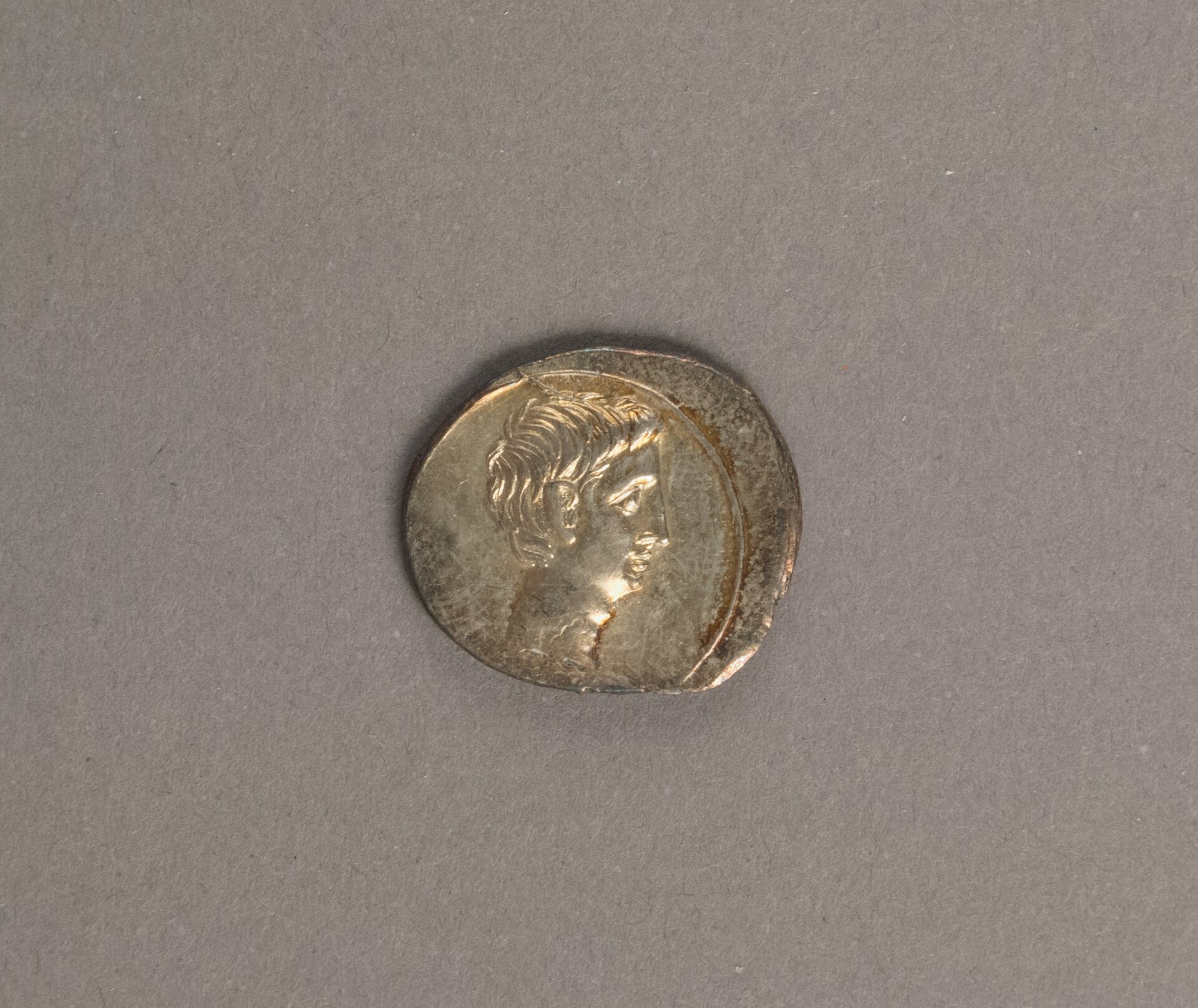 A worn silver Roman denarius showing the profile portrait of Octavian facing right