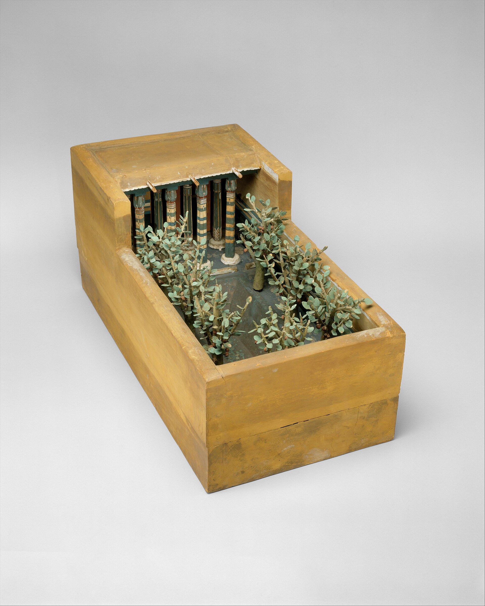 A painted wooden model of an Egyptian house porch, with a row of columns, small fig trees and a sunken water pool