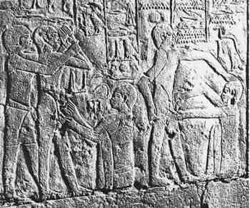 An Egyptian stone relief showing a circumcision rite being performed, figures carved standing out from a flat background
