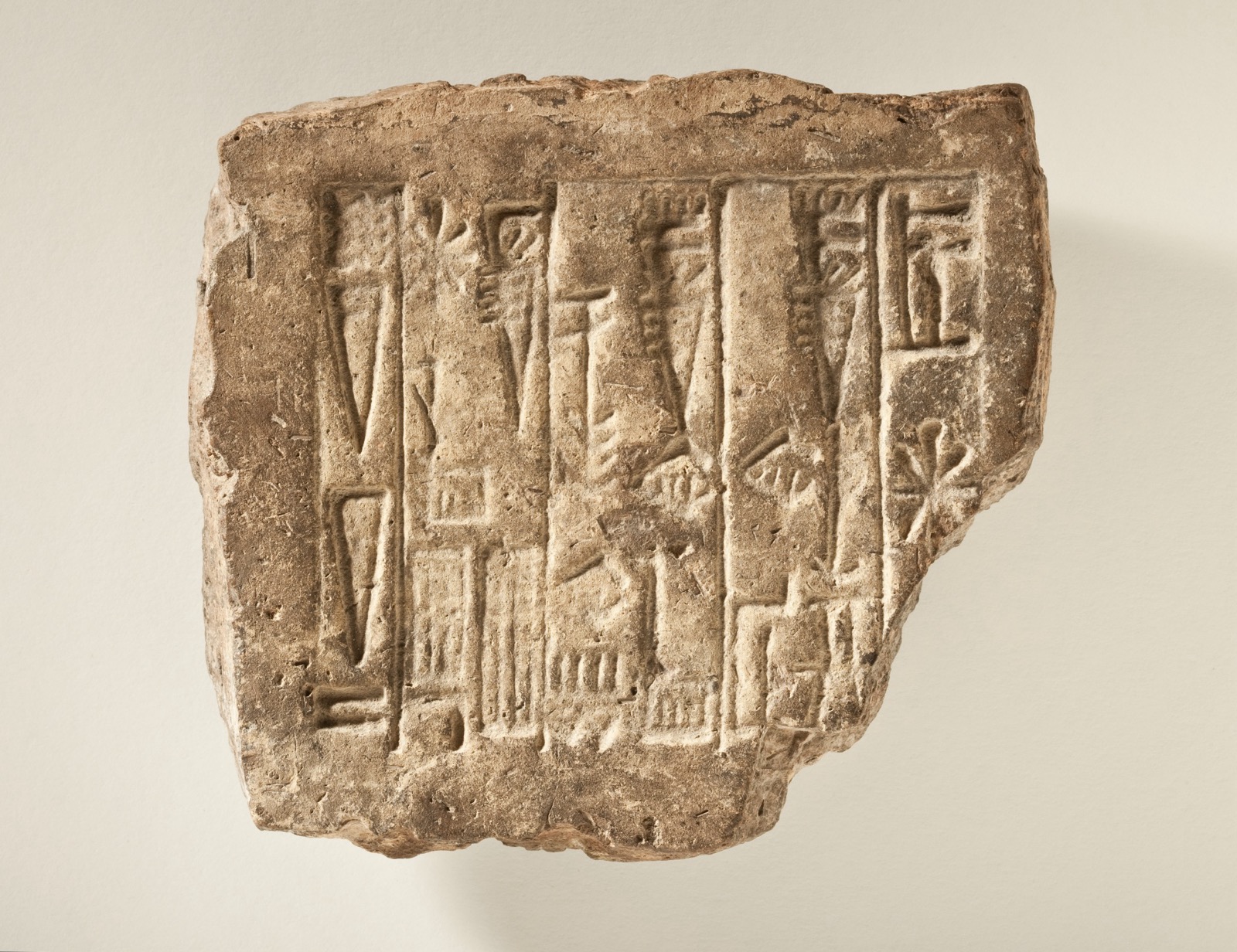 A rectangular clay brick from Mesopotamia with several lines of cuneiform stamped into its face